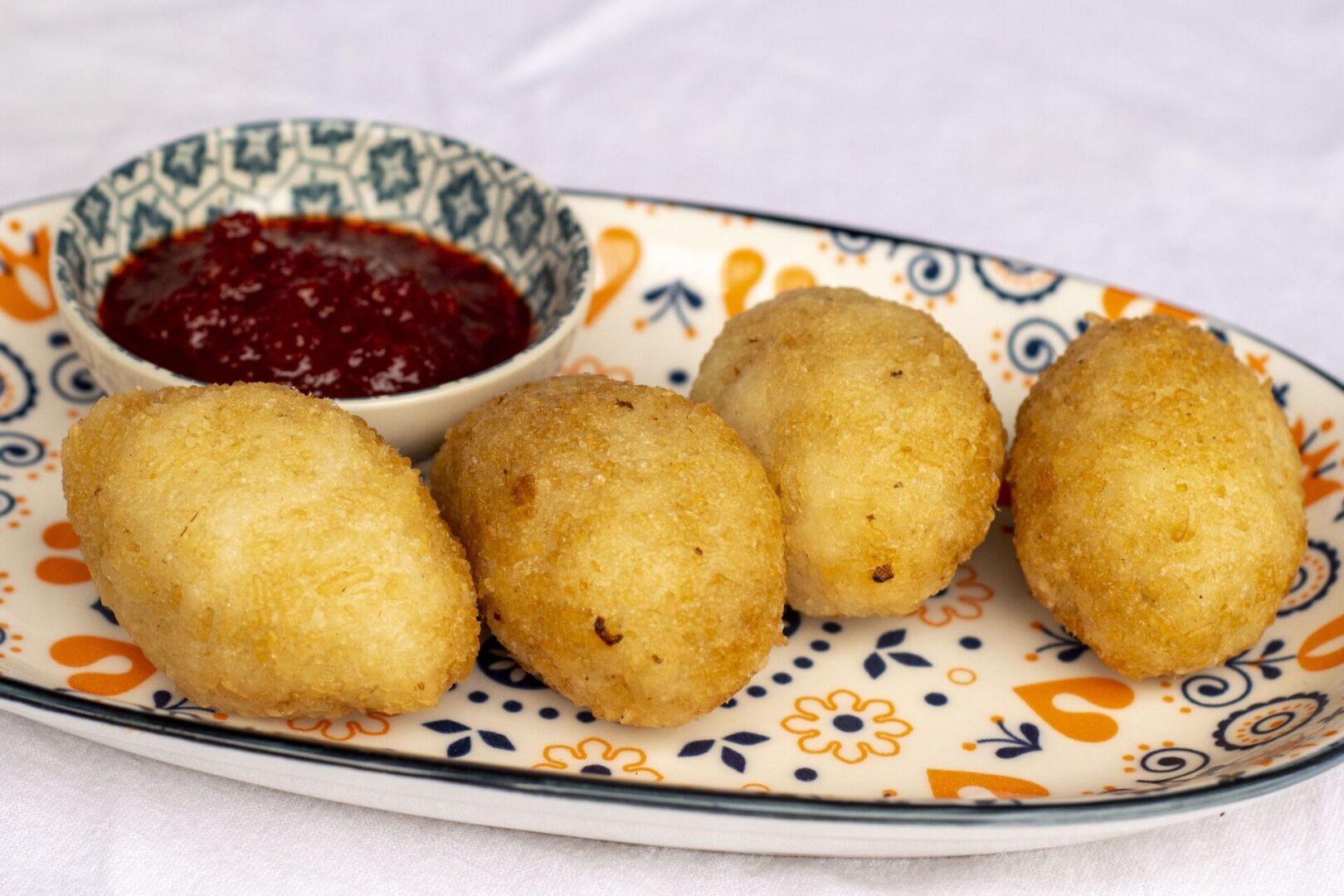 A plate of food with some fried dough balls and sauce.